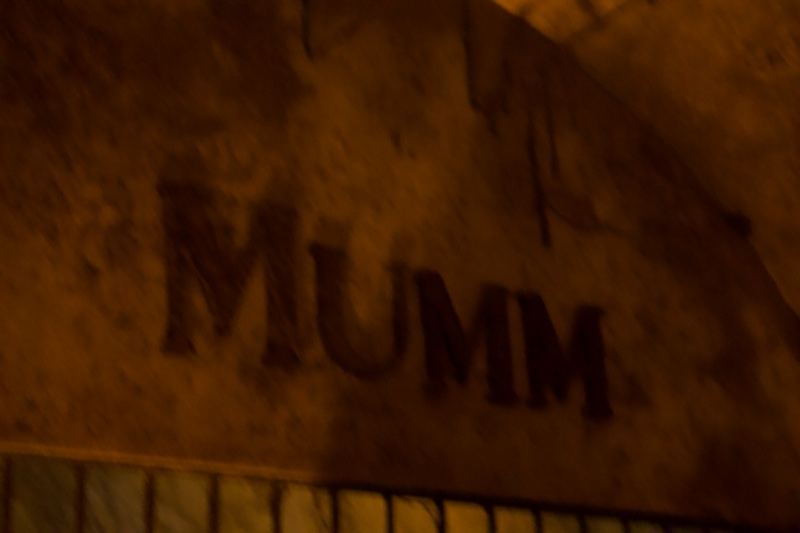 MUMM sign on dim stone wall