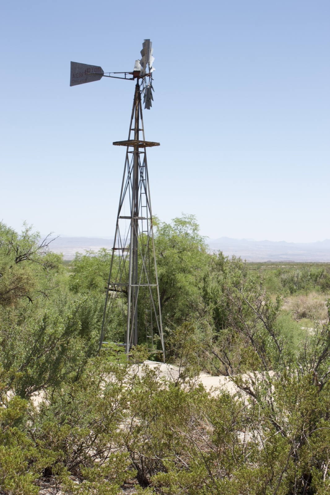 Windmill in Desert Scrub Landscape