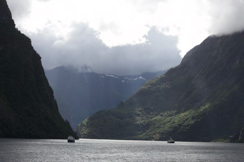 Fjord Mountains with Boats Under Clouds