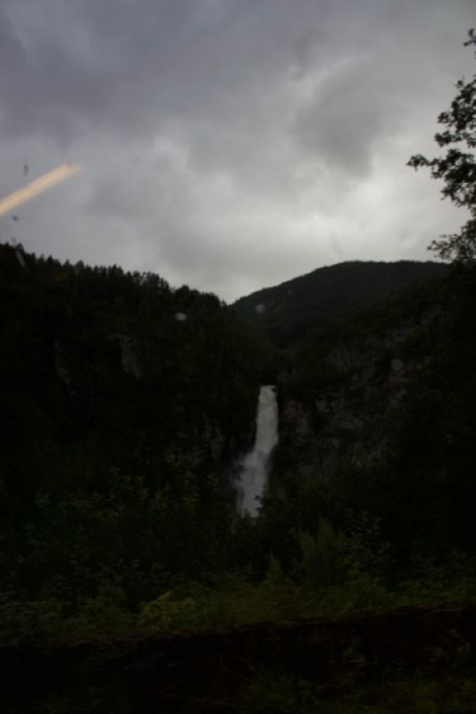 Waterfall in Mountain Valley Under Overcast Sky