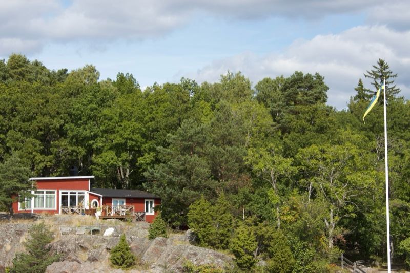 Red Cabin in Forest by Rocky Shore