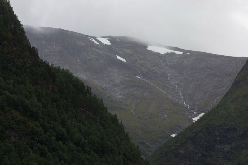 Snow-Patched Mountain Valley Under Overcast Sky