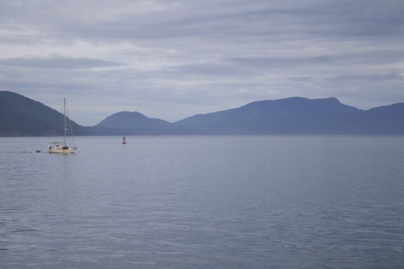 Sailboat on Calm Bay Under Overcast Sky