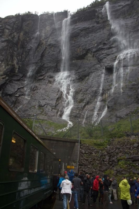 Waterfalls Cascading Over Cliff Beside Train