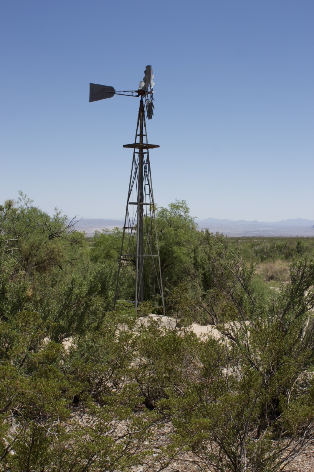 Windmill in Desert Scrub Landscape