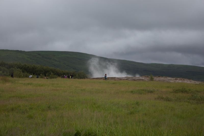 Geyser Steam Over Grassland Under Clouds