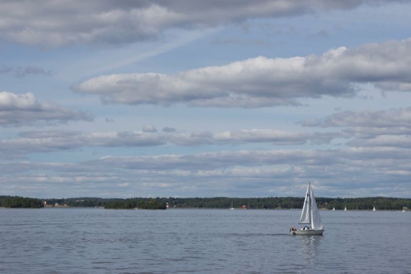 Sailboat on calm lake under cloudy sky