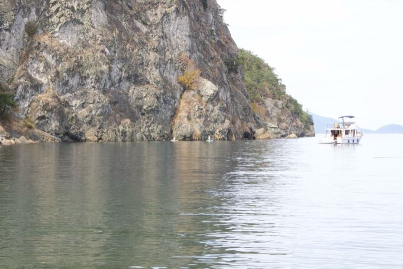 Rocky Cliff Over Calm Lake With Boat