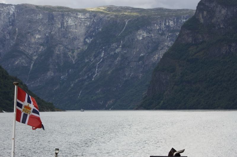 Norwegian flag over fjord mountains