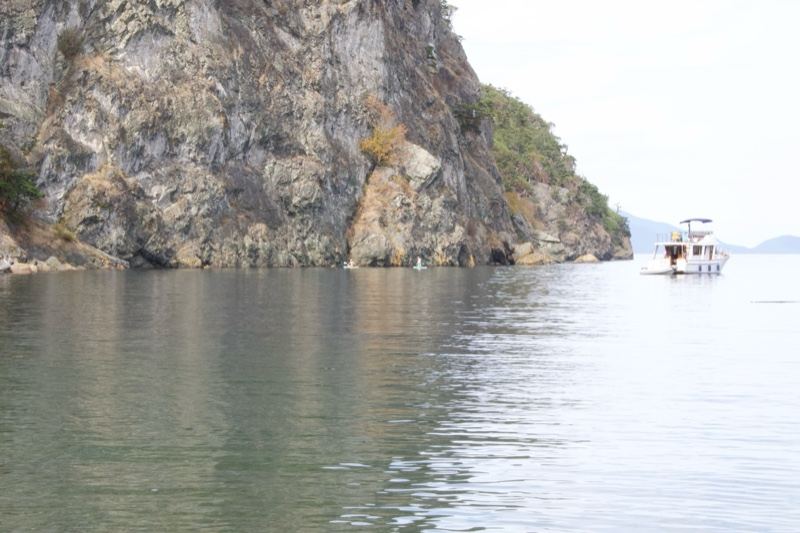 Rocky Cliff Over Calm Lake With Boat