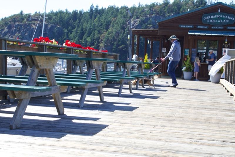 Man sweeping dock at waterfront restaurant
