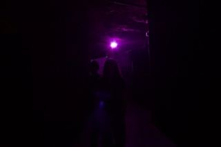 Silhouettes Under Purple Light in Dark Corridor