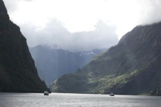 Fjord Mountains With Boats Under Clouds