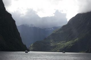 Fjord Mountains with Boats Under Clouds