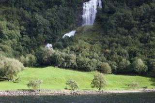 Waterfall Cascading Over Forested Cliff