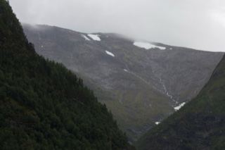 Snow-Patched Mountain Valley Under Overcast Sky